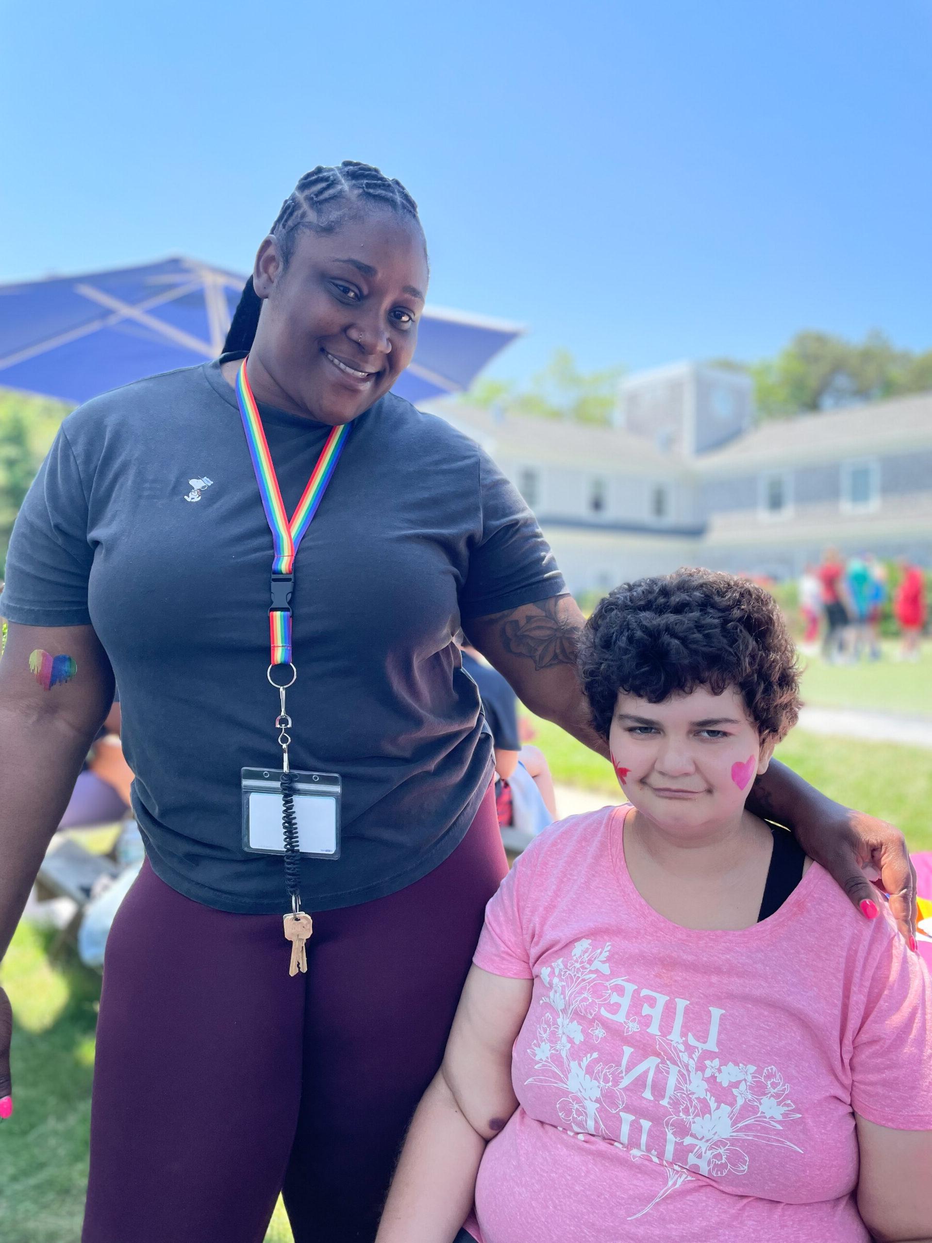 Woman standing with her arm around a younger girl. 